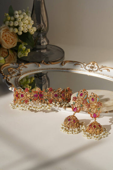 Chaya Navratan choker and jhumka earrings set with vibrant stones and pearls, styled on a mirror tray for bridal jewelry display.