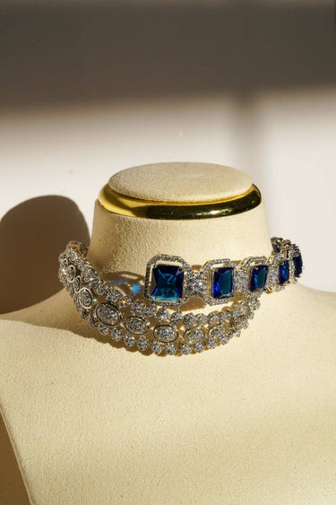 Mahi Asymmetrical Choker Necklace Set - Rhodium-plated with AD stones, available in silver & green, silver & ruby, and silver & sapphire blue, perfect for contemporary elegance.