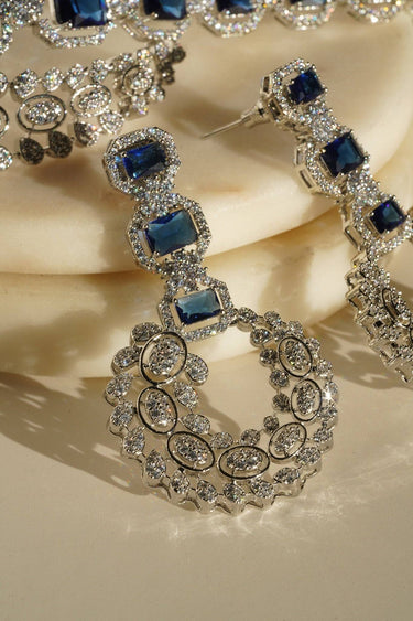 Mahi Asymmetrical Choker Necklace Set - Rhodium-plated with AD stones, available in silver & green, silver & ruby, and silver & sapphire blue, perfect for contemporary elegance.