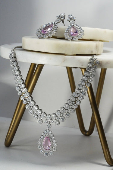 Mirah AD Necklace Set - Elegant Jewelry in pink teardrop design with CZ stones, includes necklace and earrings on marble display.
