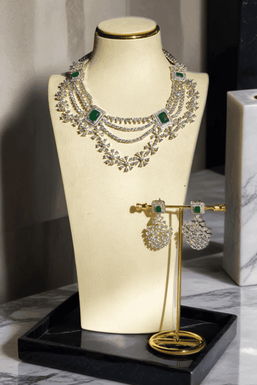 Neha Diamanté Accent Classic Necklace Set - Rhodium-plated with ruby or green accents, floral pattern, curvy layers, and matching 2-inch earrings.
