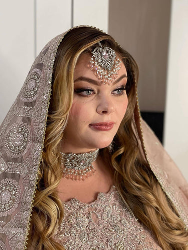 Bride in traditional attire wearing Noreen Choker Necklace Set - Elegant Pakistani Bridal Jewels with silver and pink teardrop stones.