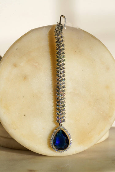 Safi - Rhodium-plated maang tikka with white American Diamonds and a sapphire blue teardrop accent from Inaury