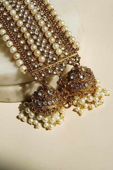 Close-up of Samia Bangles highlighting gold filigree jhumkas with pearl clusters and sparkling CZ stones, perfect for festive wear.