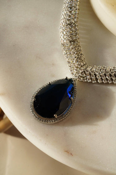 Sharmine Paved Silver Diamanté Accent Necklace Set - Rhodium-plated with Diamanté stones, featuring a large teardrop stone and chandelier earrings, available in multiple color options, perfect for modern South Asian ensembles.