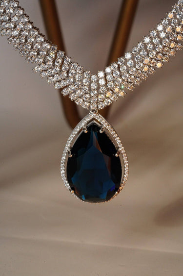 Sharmine Paved Silver Diamanté Accent Necklace Set - Rhodium-plated with Diamanté stones, featuring a large teardrop stone and chandelier earrings, available in multiple color options, perfect for modern South Asian ensembles.