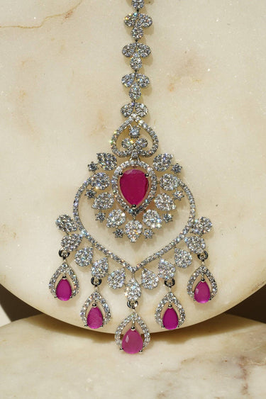 Close-up of the oversized Rhodium plated American Diamond Maang Tikka with ruby pink and green teardrop dangles