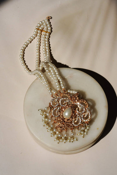 Single piece of Ira - Chandbali maang tikka in pearl variant, featuring layered pearl strands and ornate gold design with CZ stones.
