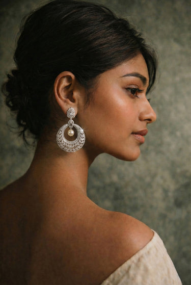 Woman wearing large, ornate earrings with a neutral background