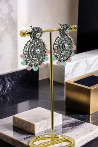 Angled view of Navya Black Plated Chandbali Earrings with intricate black plating and pastel accents, styled for festive fashion.