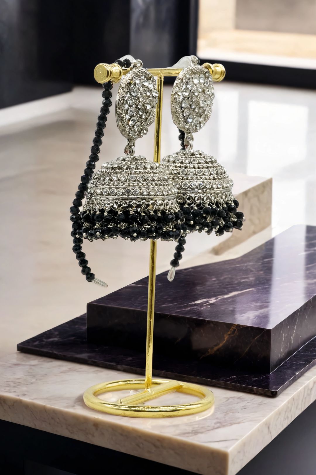Silver Tabiha Jhumka Earrings with black bead fringe, displayed on a gold stand for traditional jewelry styling.