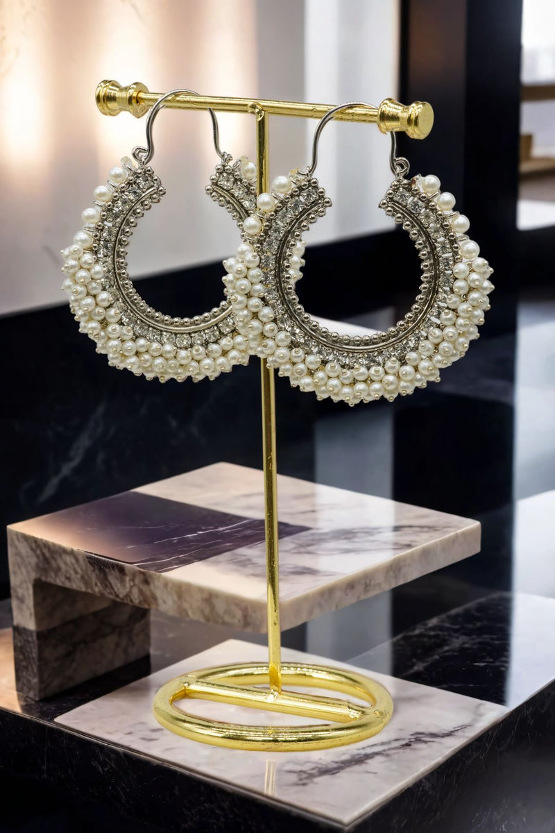 Noor Chandbali Hoop Earrings in silver-tone with white pearls, showcasing South Asian elegance on a gold display stand.