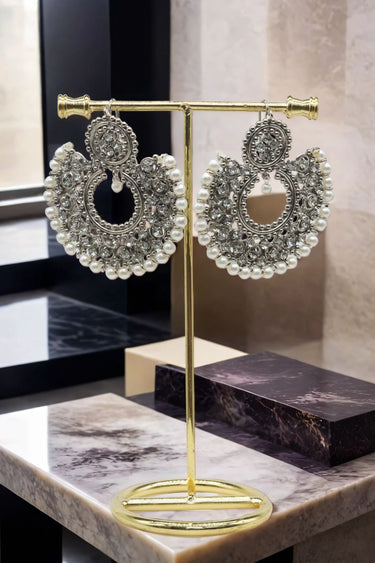 Laila Chandbali Earrings in antique gold with white stones and pearls, elegantly presented on a gold jewelry stand.