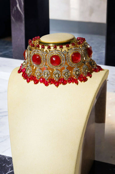 Sweta Diamante Choker Necklace featuring red doublet stones and ornate gold accents, displayed on a cream bust.