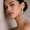 Woman wearing elegant silver earrings against a neutral background