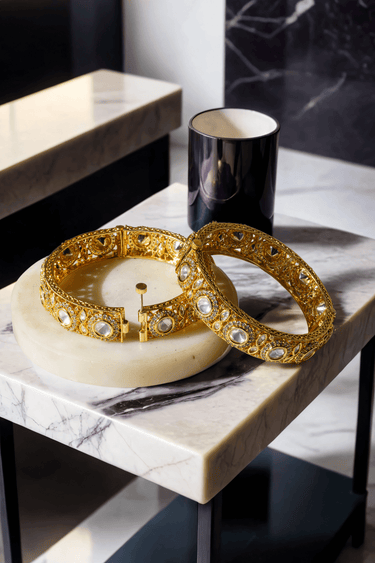 Tamina Moissanite Polki Bangles - Heritage Style | Openable gold bangles set on marble table, showcasing intricate design and openable clasp.