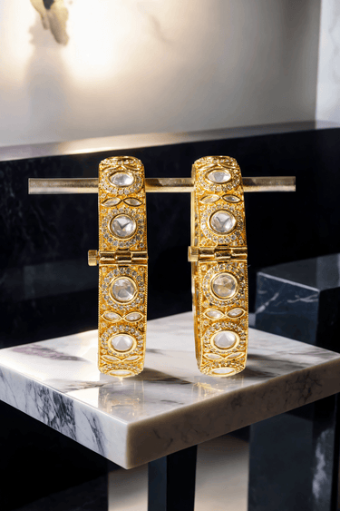 Tamina Moissanite Polki Bangles - Heritage Style | Openable close-up of bangles on marble, showing intricate gold filigree and moissanite accents.