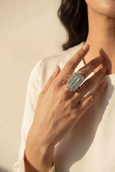 Hand wearing a silver-toned adjustable baguette diamante statement ring with mint green center stone - South Asian jewelry - Inaur