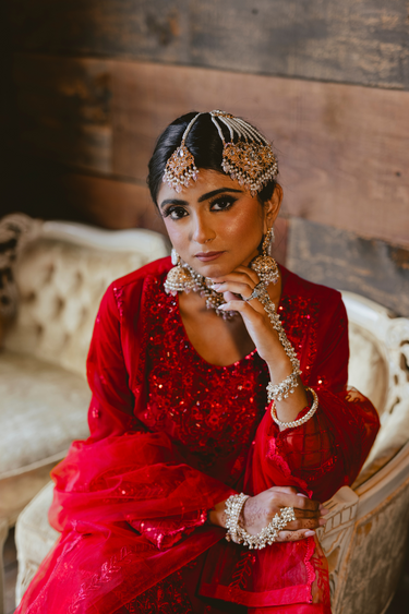 Bride seated in red outfit wearing Sareena Mirror Choker Set - Zircon & Pearl, styled with matching accessories for a complete bridal ensemble.