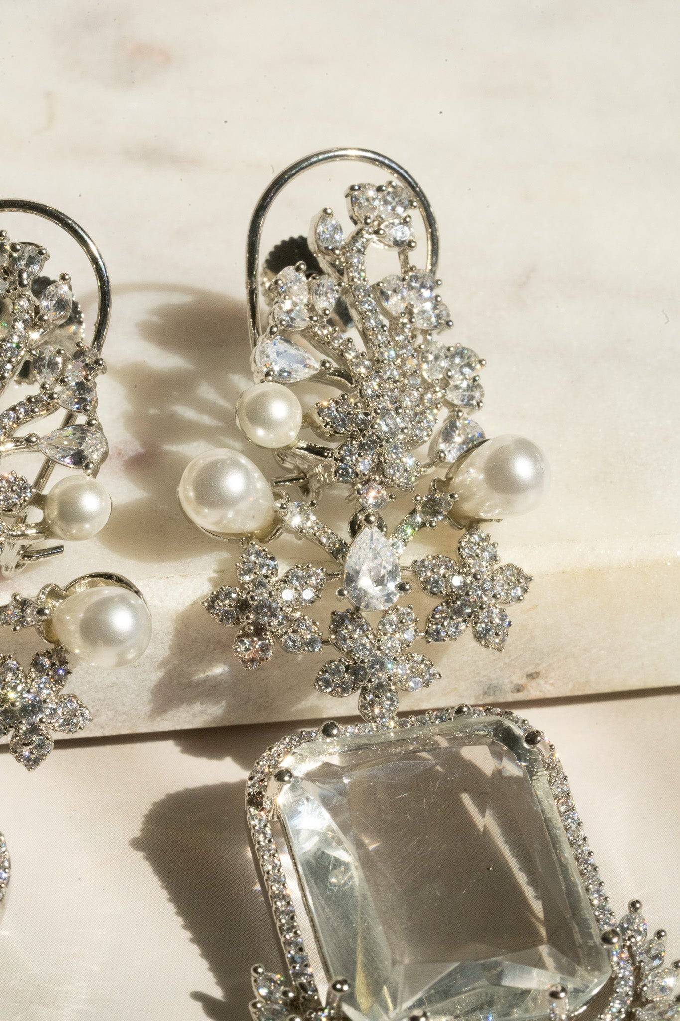 Detailed view of floral and pearl embellishments on Aayat Statement Earrings in crystal white. Elegant rhodium-plated dangle design.
