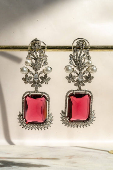 Aayat Statement Earrings in ruby red featuring a bold gemstone center, floral pavé detailing, and pearl embellishments. Rhodium-plated danglers.