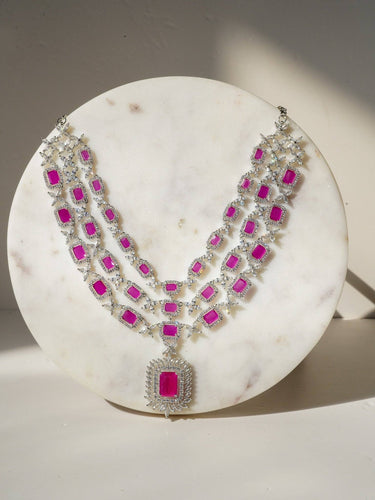 Amisha Triple Layer Diamante Accent AD Necklace Set in gold or rhodium-plated silver finish with color options of silver & sapphire blue, silver & green, gold & green, and silver & ruby, featuring floral and cushion cut stone patterns with matching earrings.