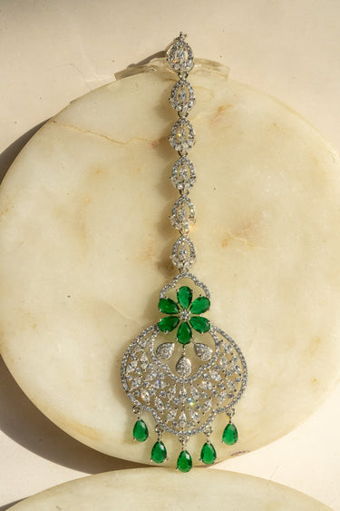 Rhodium-plated floral maang tikka with AD stones in a silver and green from Inaury