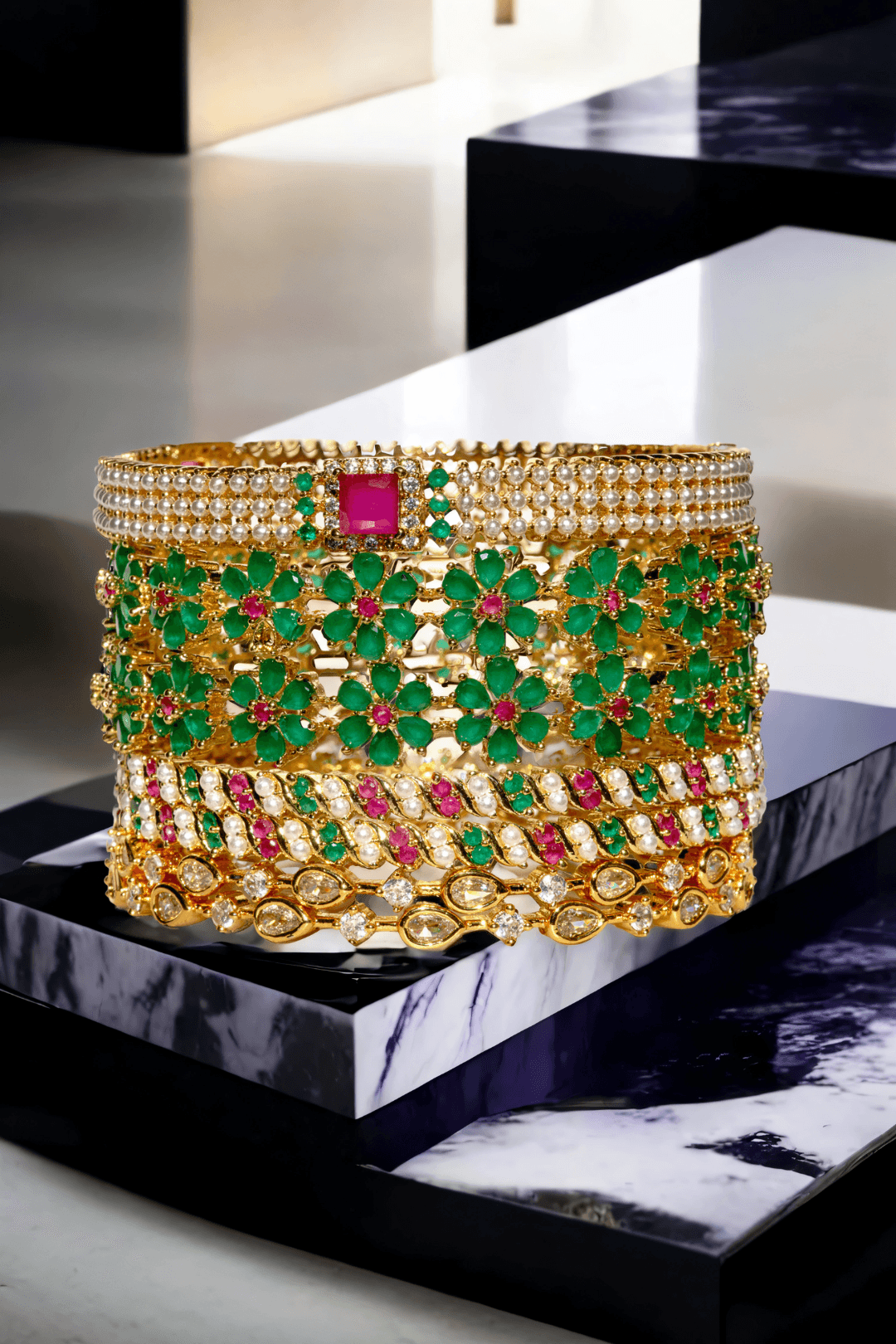 Front view of Arika floral gold-plated bangle set with emerald and ruby stones. Luxurious 7-piece jewelry for festive occasions.