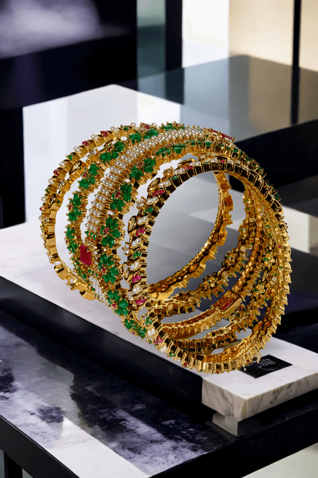 Side view of Arika gold-plated floral bangles with emerald and ruby accents. Traditional jewelry set for festive and bridal looks.