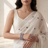 South Asian woman wearing a white saree with sapphire blue and silver bangles from Inaury in a bright room.