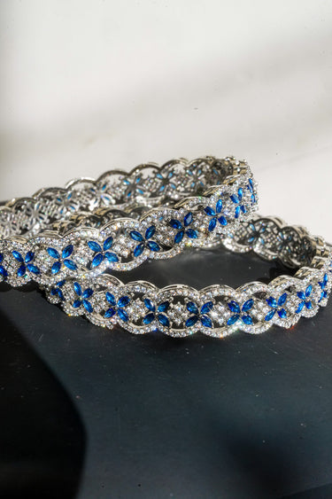 Two silver bracelets with blue stones on a dark surface