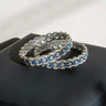 Rhodium plated Indian bangles with sapphire blue and white stones on a black jewelry box.