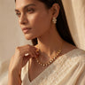 Side profile view of a model styling the delicate single-strand Dilara heart Kundan necklace over a white embroidered bridal saree.