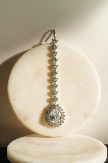 Close-up of clear teardrop Amore AD Maang Tikka on marble coaster