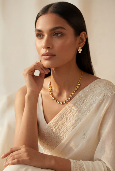 An elegant lifestyle model showcase of the delicate gold-plated Dilara Kundan necklace and clover-style stud earrings for minimalist South Asian bridesmaid outfits.