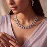 Close-up of Julie rhodium-plated crescent wave necklace and AD stone drop earrings worn with a lavender saree.

