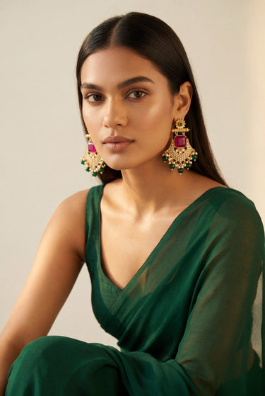 An elegant front portrait of a model highlighting the symmetry and vibrant gemstone arrangement of the Kavya gold-plated statement chandbali earrings.