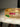 An extreme close up catalog photograph focusing on the flawless channel set ruby red and emerald green baguette stones along the rim of the gold Kyra bangles.