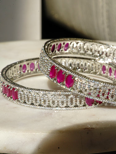 An overlapping flat lay view showcasing the seamless eternity structure and high clarity crystal setting of the silver toned Kyra AD stone bangles.
