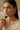 An elegant three-quarter lifestyle portrait of a model showcasing the gold-plated Mehr single-strand teardrop Moissanite necklace and matching cascading triple-tier drop earrings.