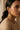A macro profile shot of a model wearing the blush pink and mint green Mira peacock statement earrings to display the scale and fit against the jawline.