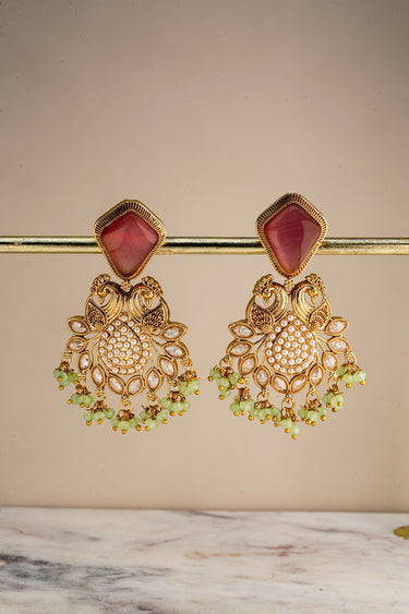 A front studio view of the pink and mint green Mira peacock earrings hanging on a display bar to show the detailed pearl-paved dome design.