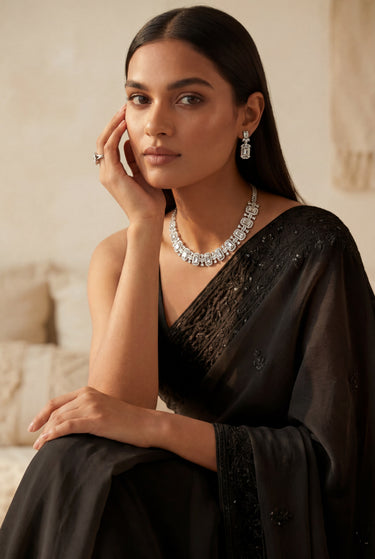 A lifestyle studio portrait of a model wearing the rhodium-plated Shanaya geometric choker set paired with an elegant black saree.