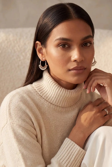 A front view studio portrait of a model styling the silver rhodium Sia beaded hoop earrings.