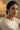 A close up three quarter lifestyle portrait of a model styling the mehndi gold plated Zoe geometric drop earrings with a cream colored outfit.