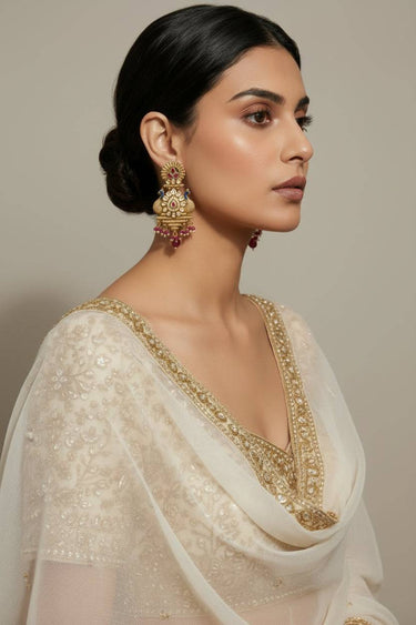 Inaury Adrita Kundan Meenakari Peacock Drop Earrings in Ruby Gold worn by model in ivory saree — full four-tier gold drop with peacock motif and ruby bead fringe, side profile view