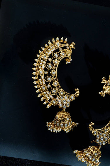 Maharani Ear Cuffs with Jhumka in Pearl White — gold-plated crescent ear cuffs with AD stones, peacock motif, and jhumka drop on dark background