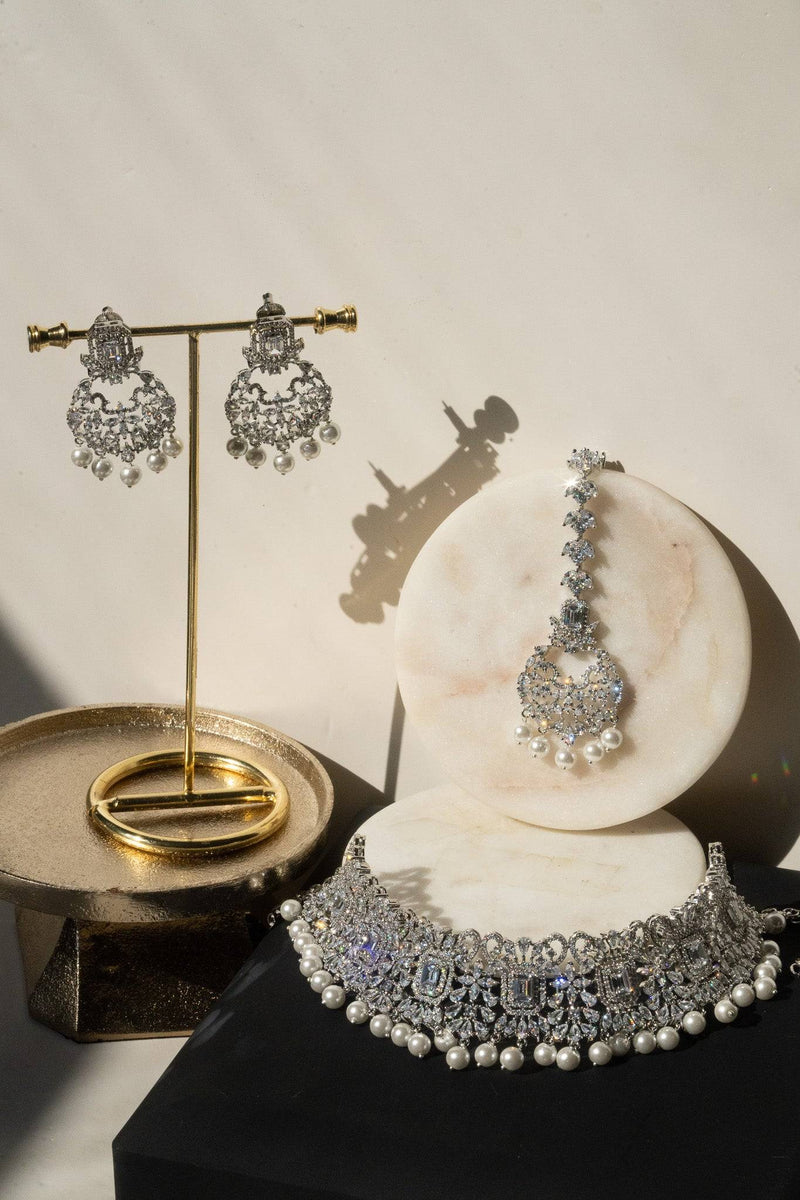 Silver jewelry set with earrings and a necklace on a marble surface.