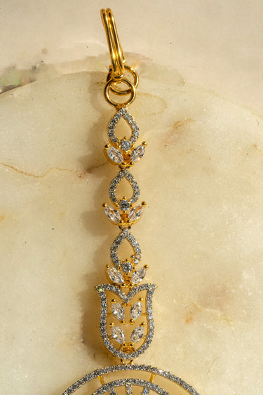 Round-shaped maang tikka with teardrop AD stones in gold plating with white accents from Inaury