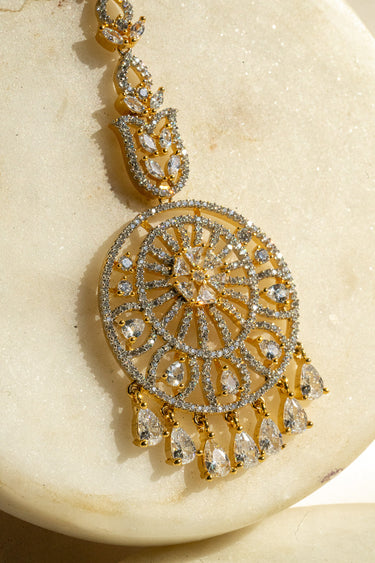 Round-shaped maang tikka with teardrop AD stones in gold plating with white accents from Inaury